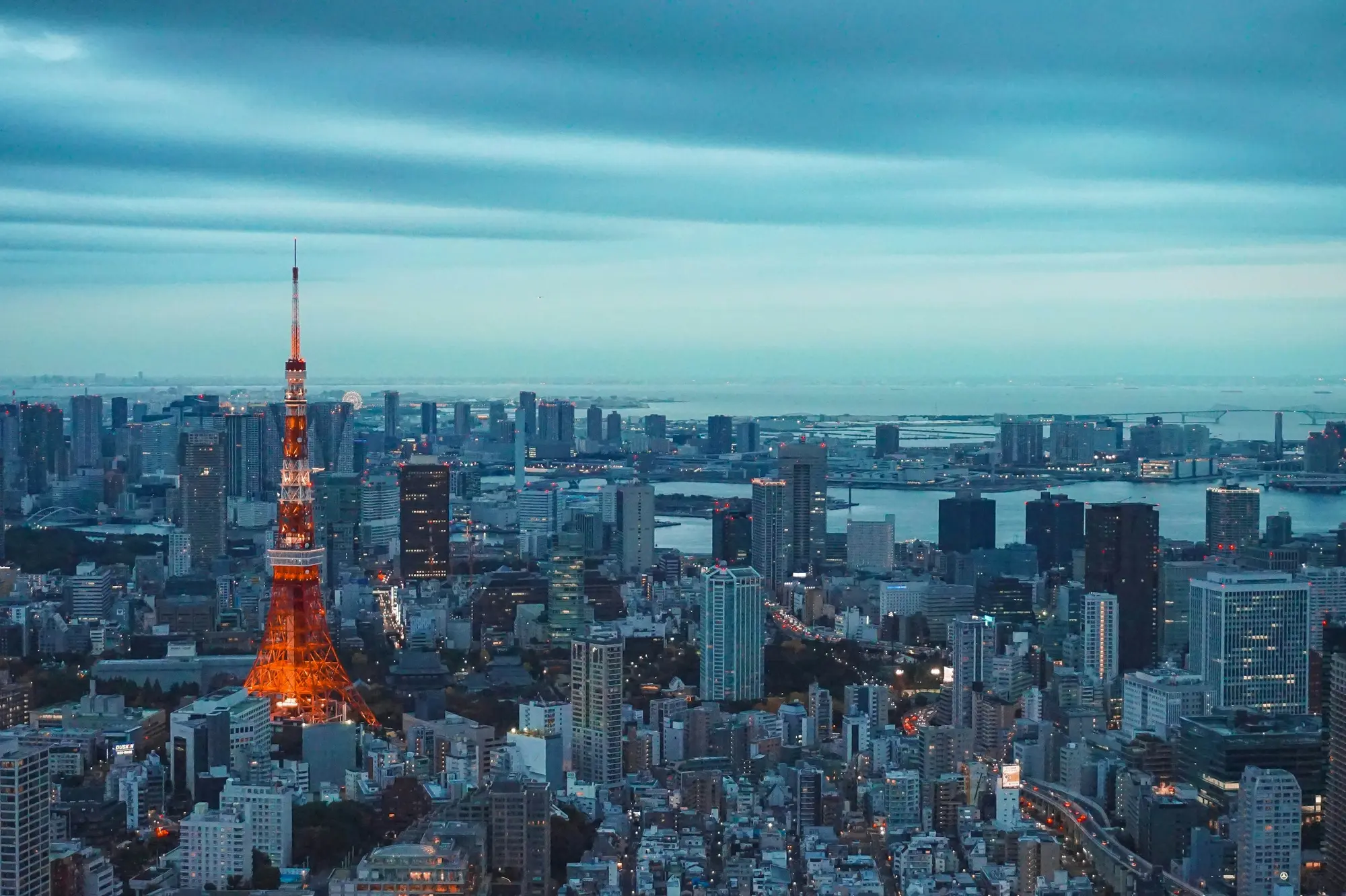 Tokyo city street at night, neon signs and pedestrians visible along a busy urban avenue