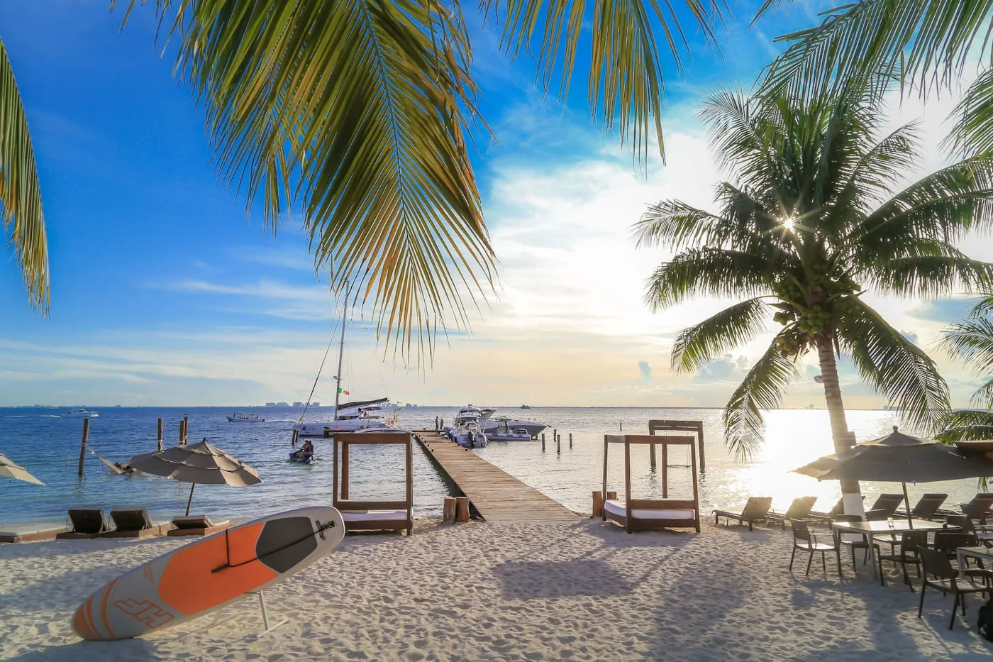 People relaxing on a bright white-sand Caribbean beach with shallow turquoise water at Isla Mujeres